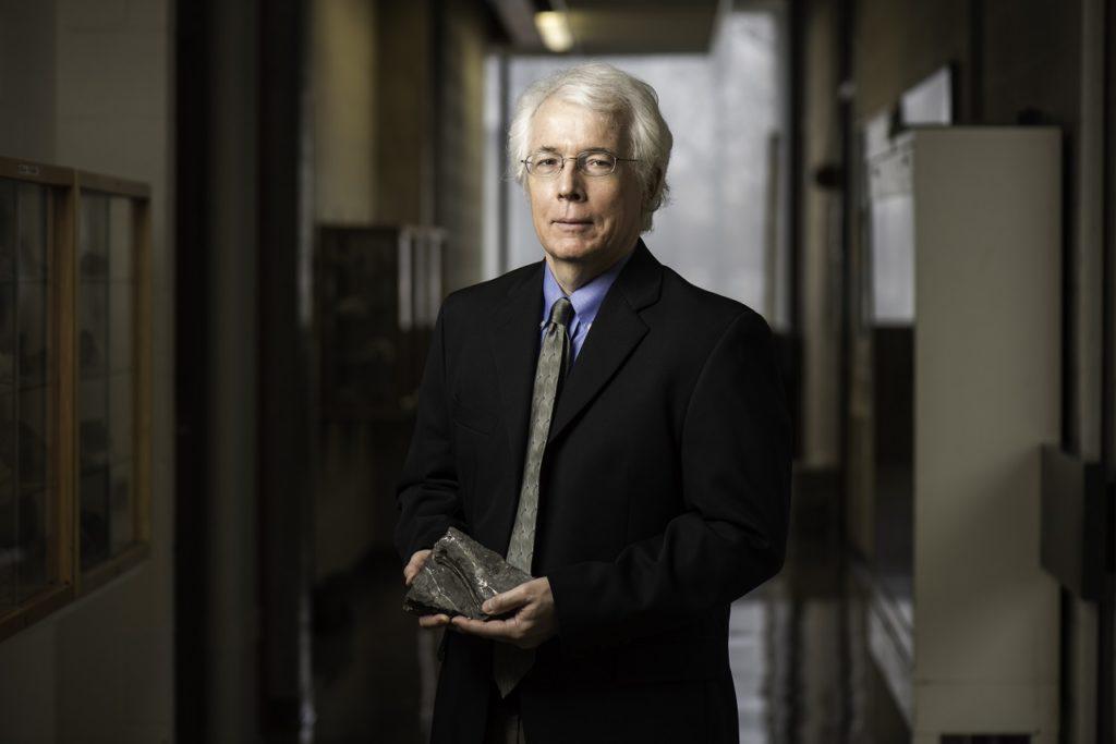 约翰·塔都诺教授拿着一块化石，作为他澳门威尼斯人网上赌场工作的一部分
